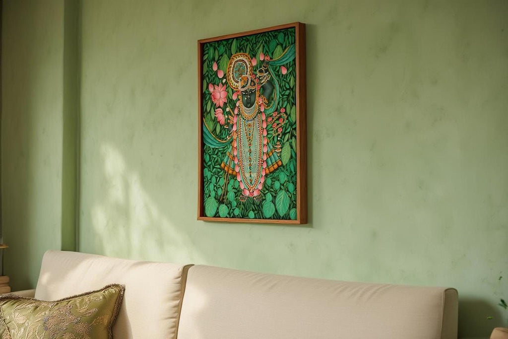 a framed painting of a colorful, intricate depiction of a Hindu deity, hanging on a green wall above a white couch.