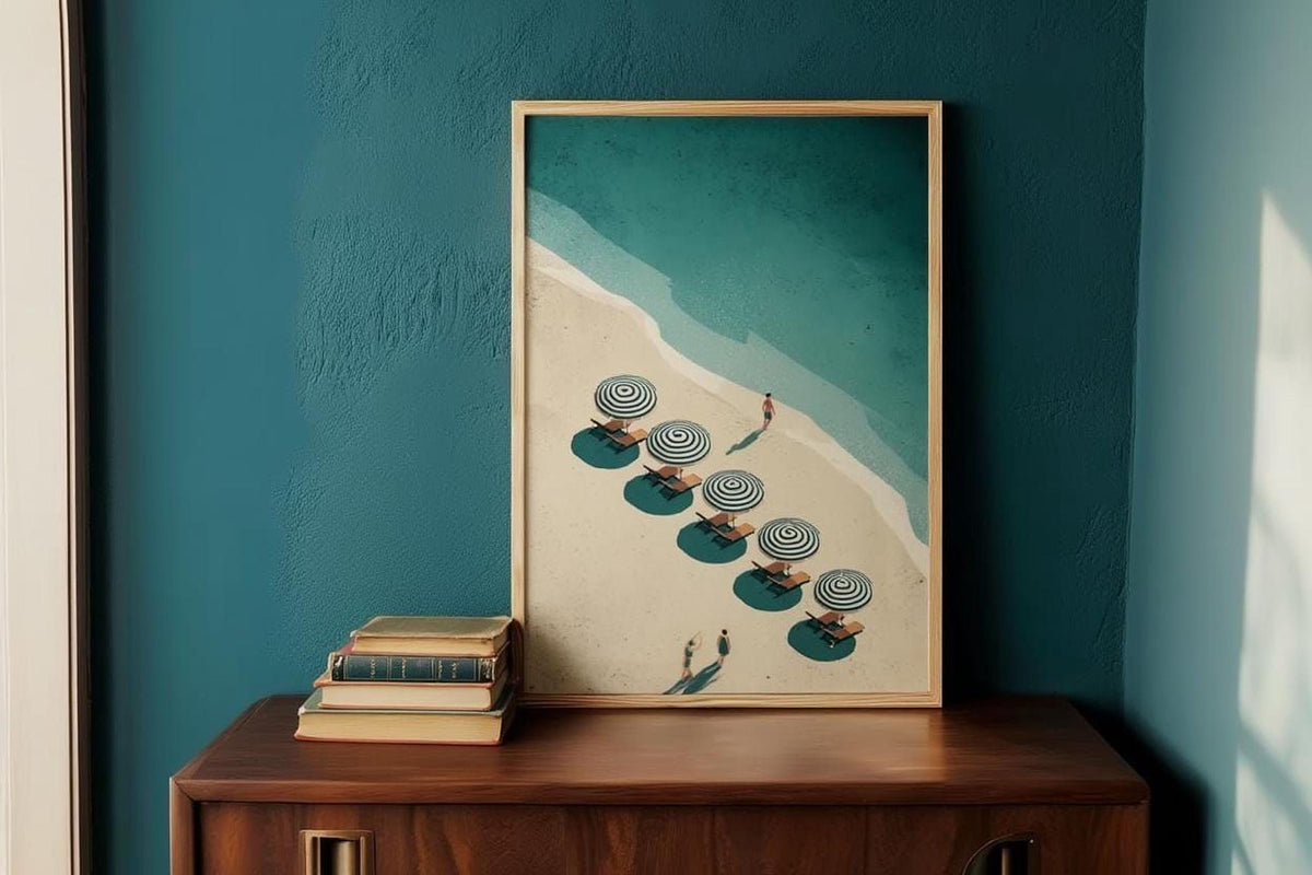 a framed artwork depicting a beach scene with a line of black and white umbrellas on the sand, with a person walking along the beach.