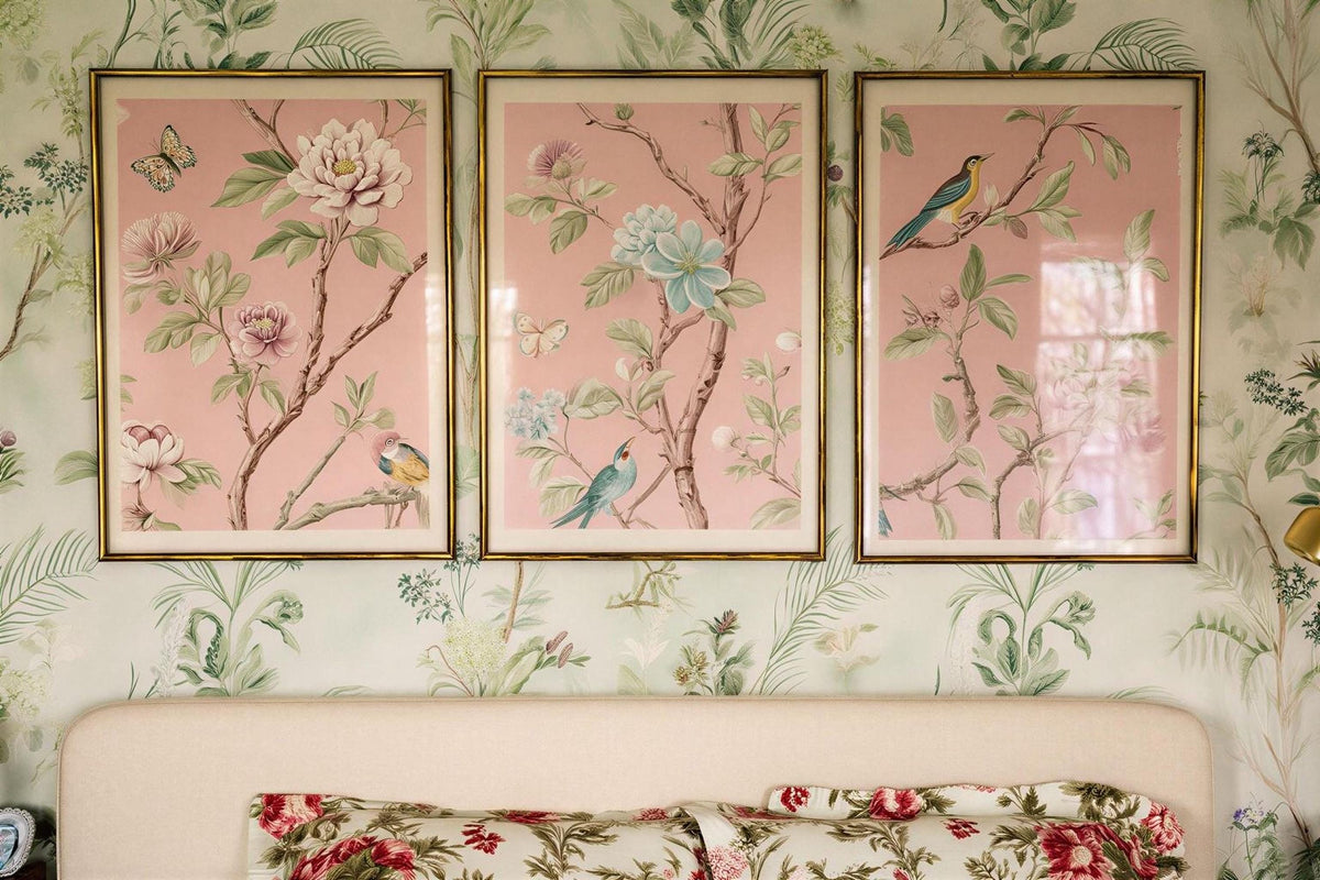 a bedroom with a white headboard and floral bedding. Above the bed, there are three framed pictures of flowers hanging on the wall.