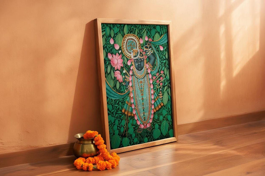 a framed painting of a deity, surrounded by a green background and adorned with flowers and leaves. Next to the painting, there is a small brass pot and a garland of orange flowers, creating a serene and spiritual atmosphere.