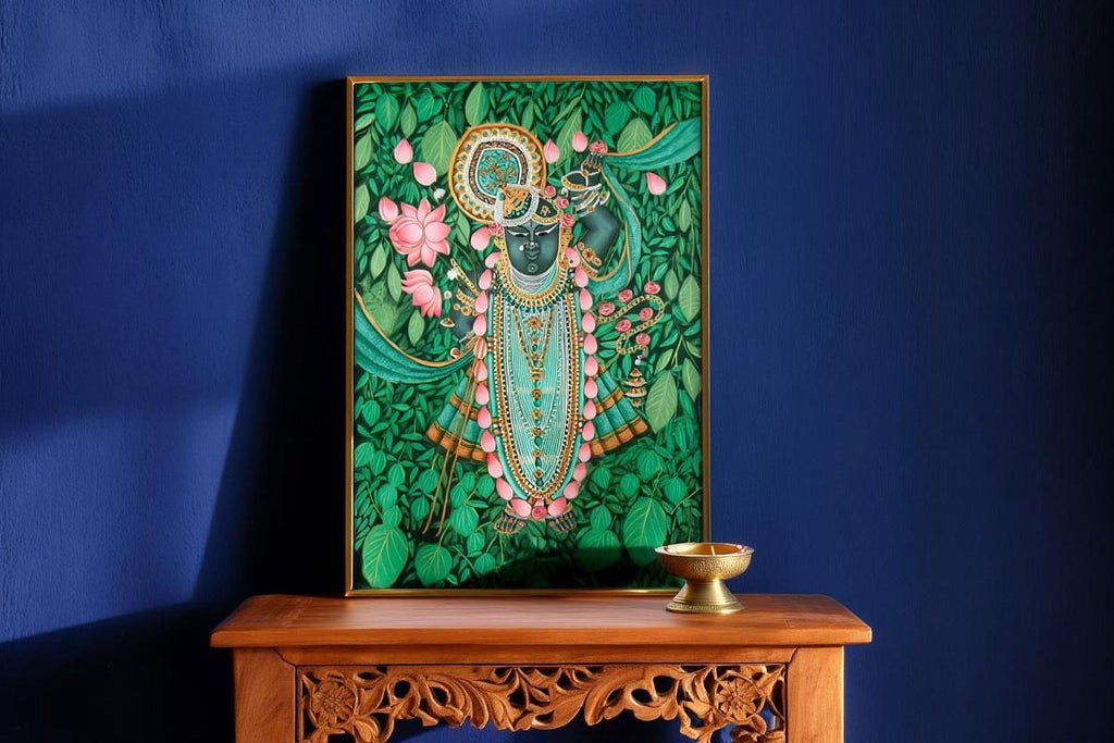 a painting of a deity with a green background and pink flowers, displayed on a wooden table against a blue wall.