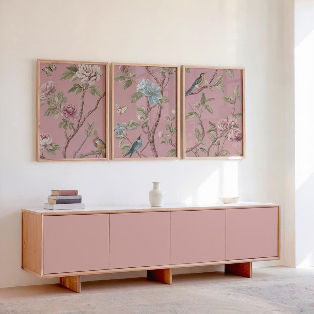 a pink cabinet with three framed floral wall art pieces above it, creating a cohesive and visually appealing design.
