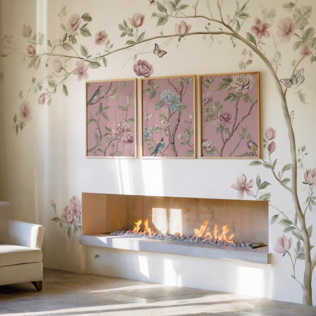 a cozy living room with a fireplace, a white sofa, and a wall adorned with three framed floral paintings. The paintings depict pink flowers and butterflies, creating a warm and inviting atmosphere.