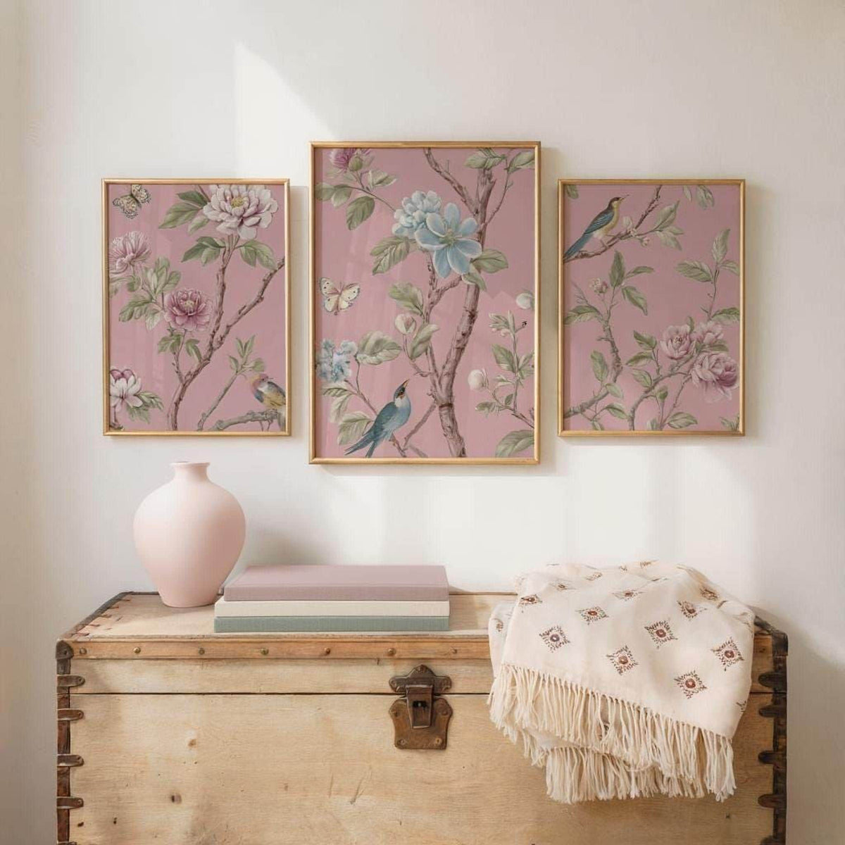 a wooden trunk with three framed floral paintings hanging above it, creating a decorative and harmonious display.