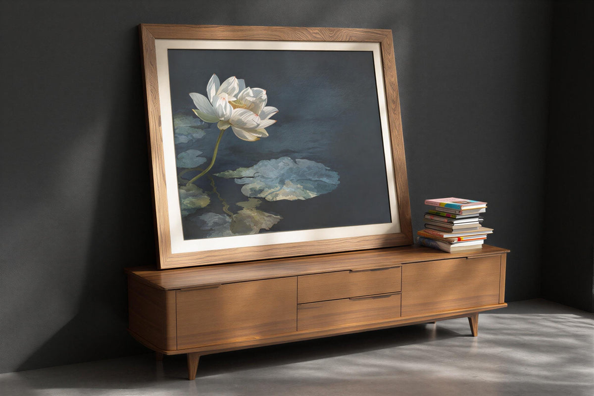 Framed white lotus wall art leaning on a low wooden credenza, teal and charcoal water tones, Asian botanical wall decor styling