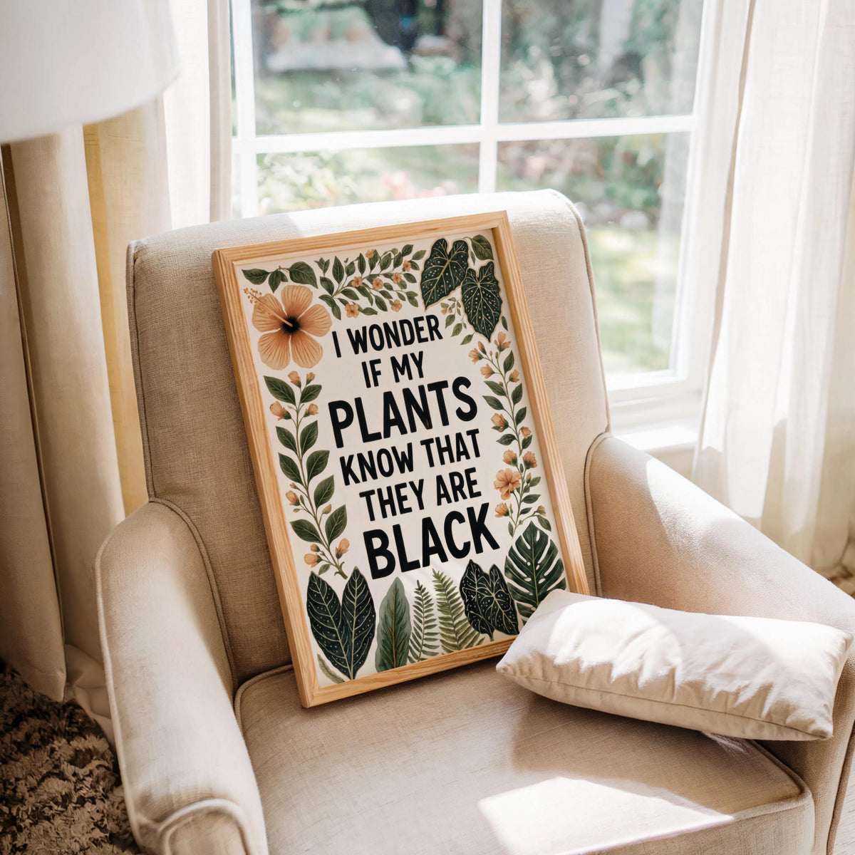Cozy armchair by window, framed typography print leaning on cushion, playful black plant lover wall art