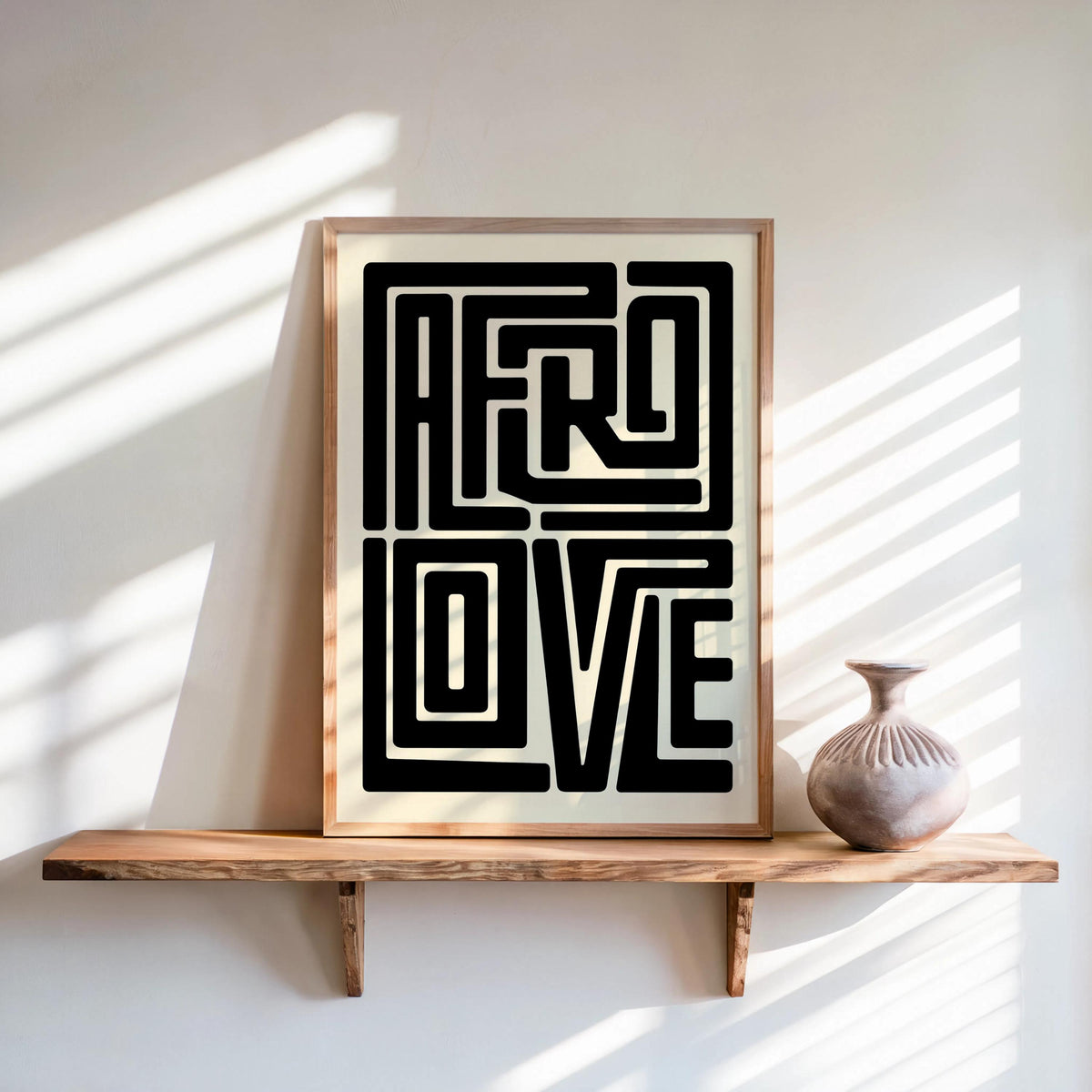 Afro Love wall art framed print on floating wood shelf, sunlit wall, small ceramic vase nearby