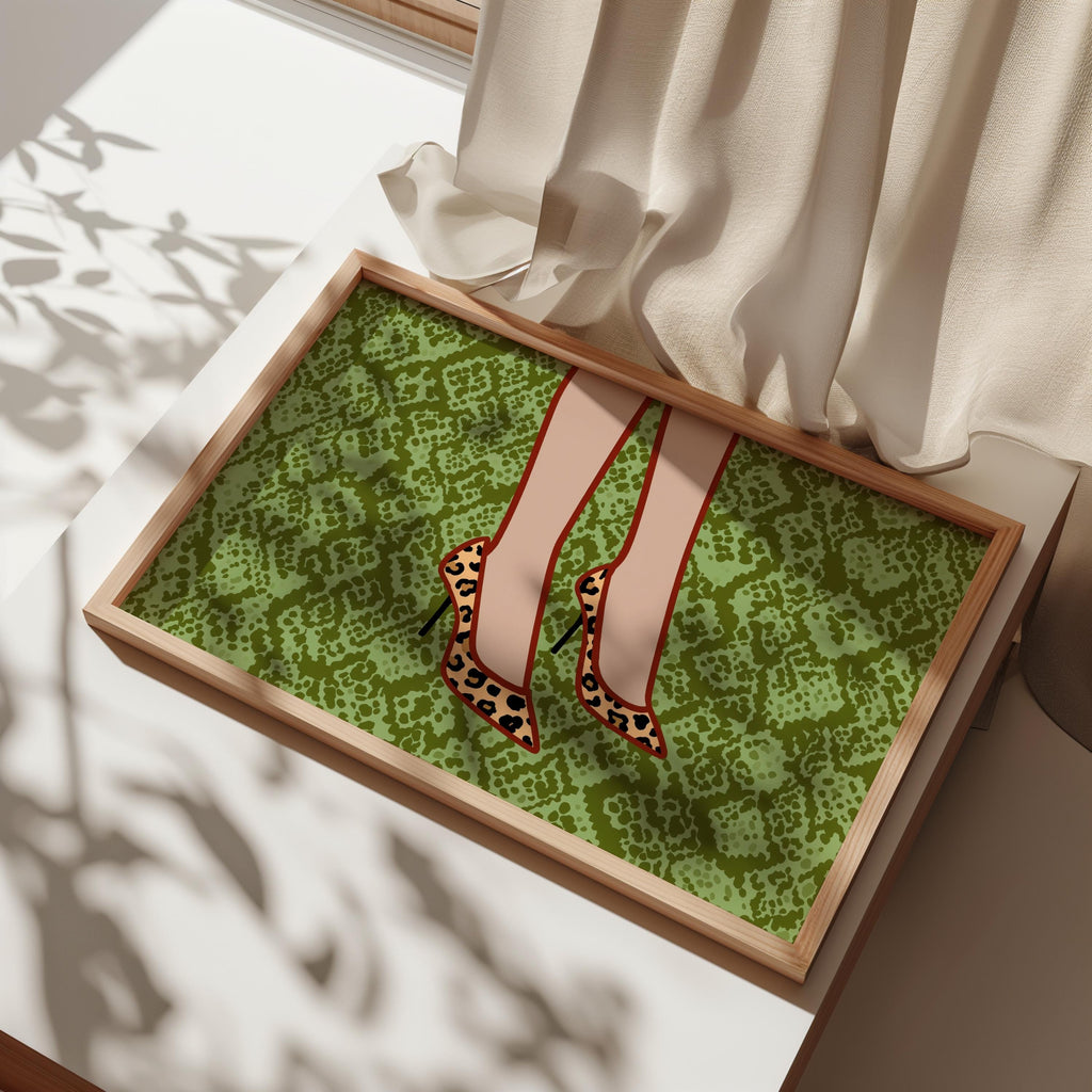 Framed print angled on bed with draped linen, leopard print heels wall art detail, textured green snake background