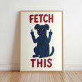Framed cream poster leaning on floor, navy dog silhouette with sunglasses, rust red FETCH THIS text, funny dog wall art