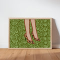 Framed leopard print heels wall art leaning against white wall on oak floor, bold green snake background, spotted pumps
