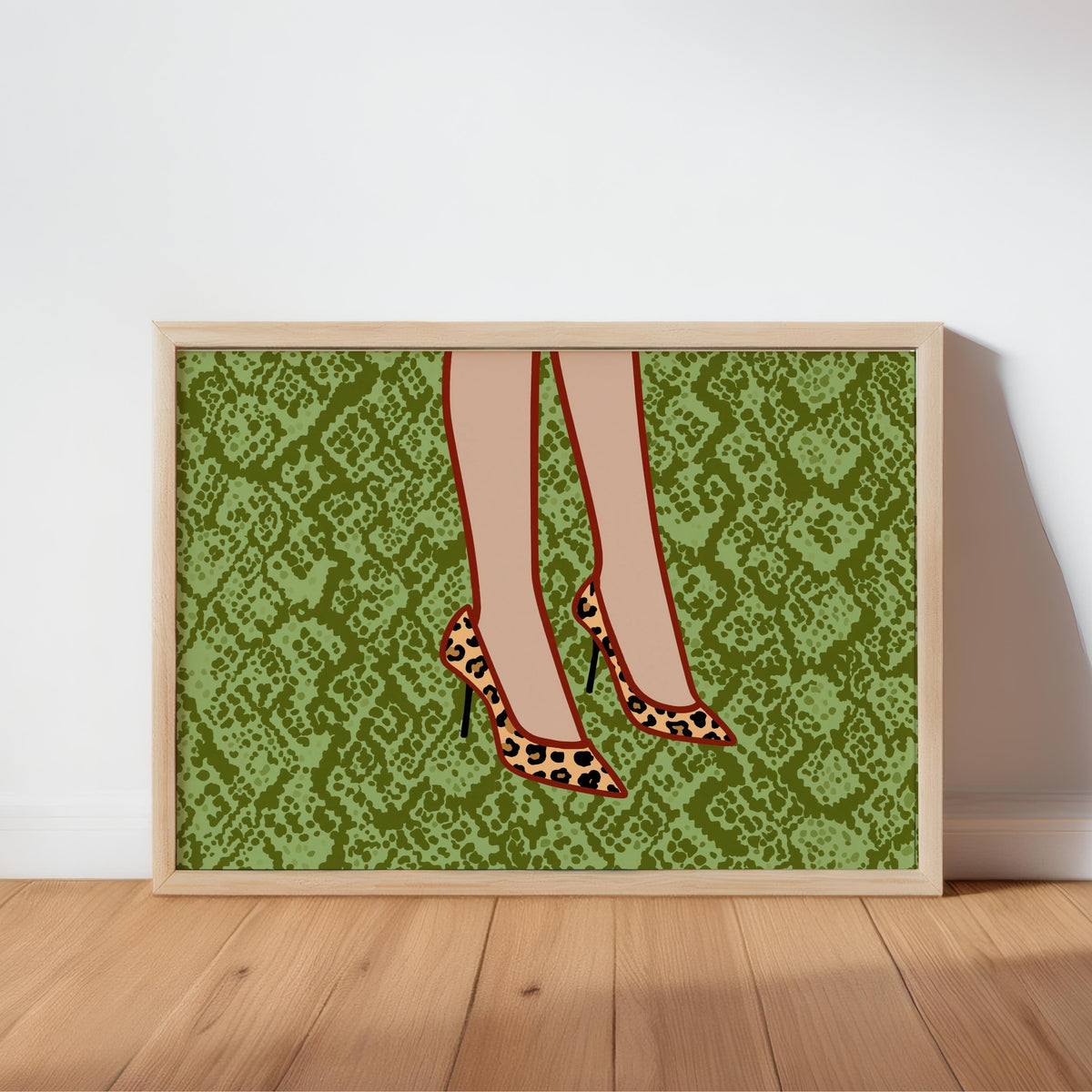 Framed leopard print heels wall art leaning against white wall on oak floor, bold green snake background, spotted pumps