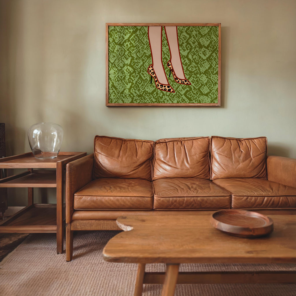 Living room scene with leopard print heels wall art above leather sofa, green snake-print backdrop, glam dressing room decor