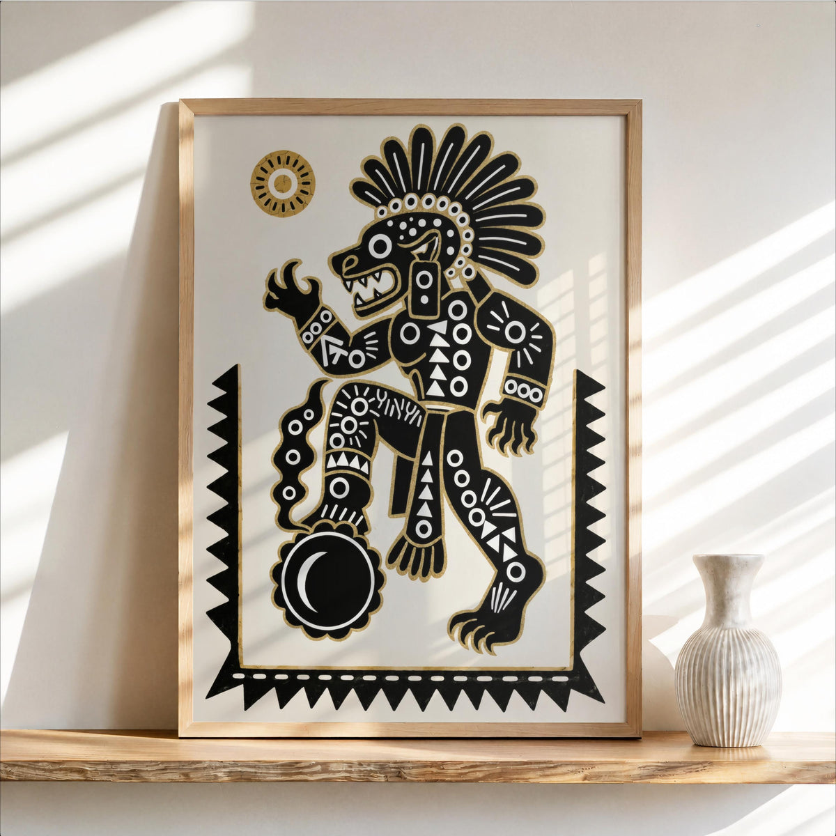 Framed Tezcatlipoca art print leaning on warm wood shelf, bold black white gold, vase nearby