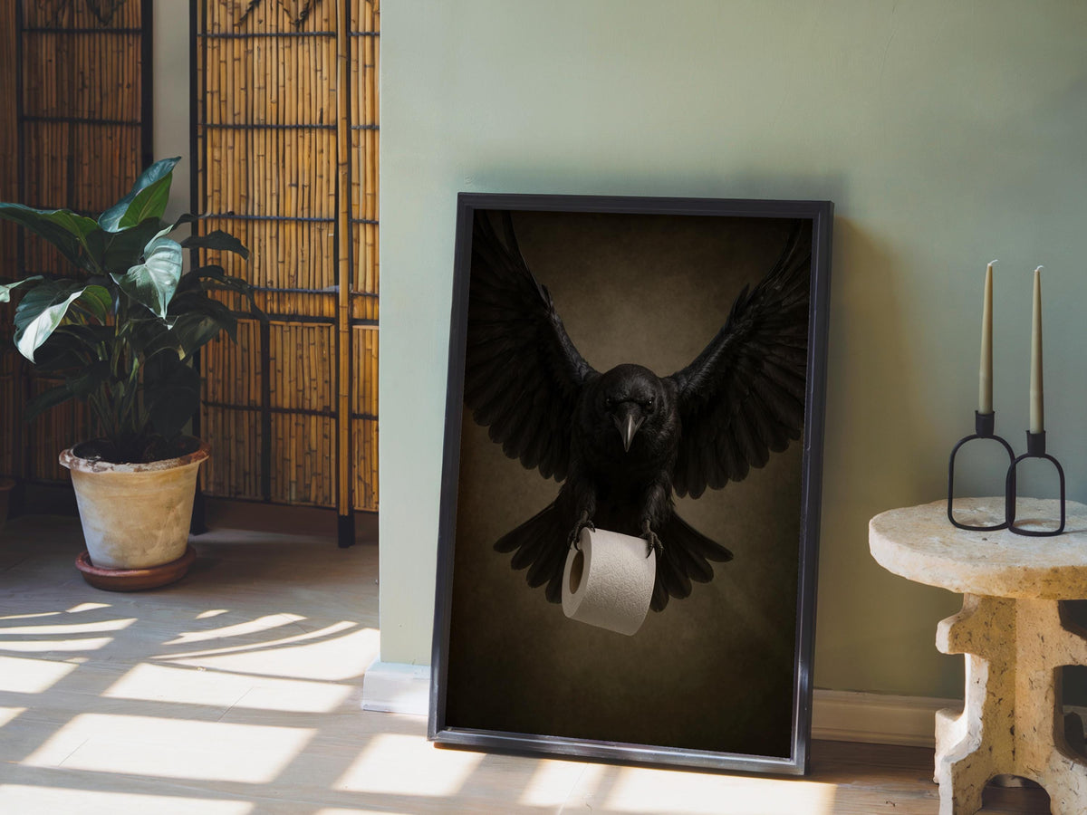 Sunlit floor vignette with raven bathroom wall art propped near a plant, gothic crow holding a toilet roll.