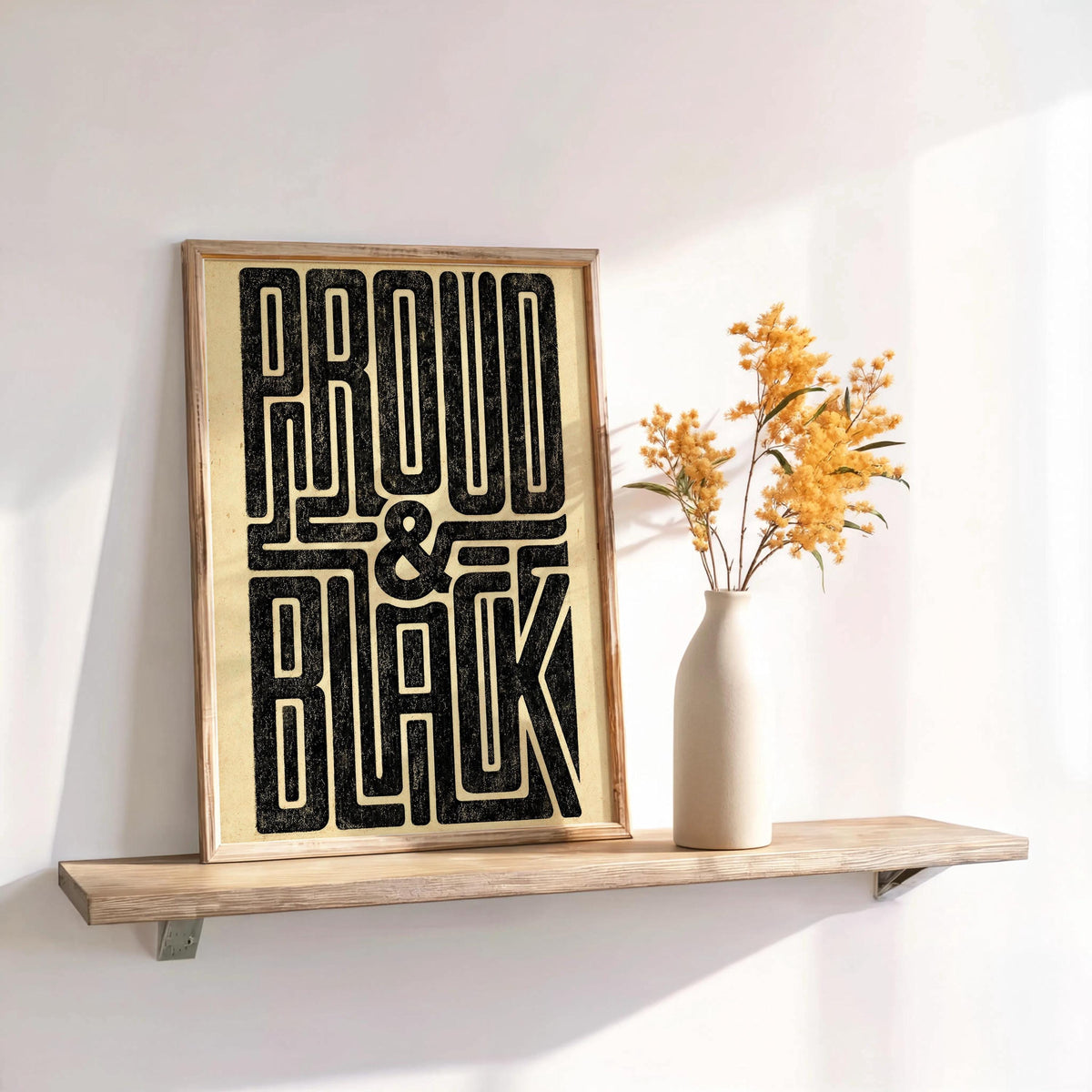 Narrow shelf display with Proud and Black poster, dried flowers in a vase, warm retro typography vibe