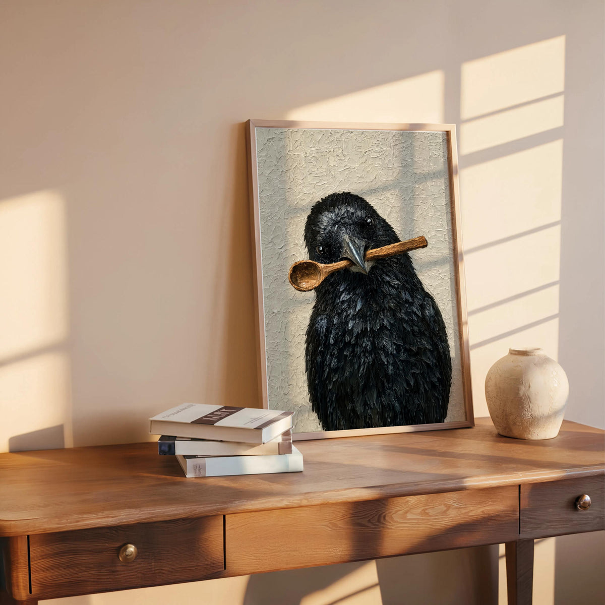Funny crow art print propped on a wooden desk, warm sunlight, ceramic vase and stacked books for cozy styling