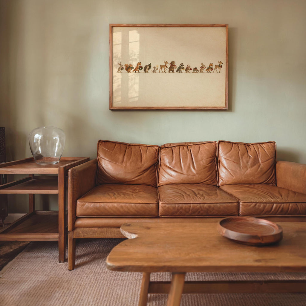 Small framed woodland animal Christmas print over a leather sofa, cozy living room vignette, side table