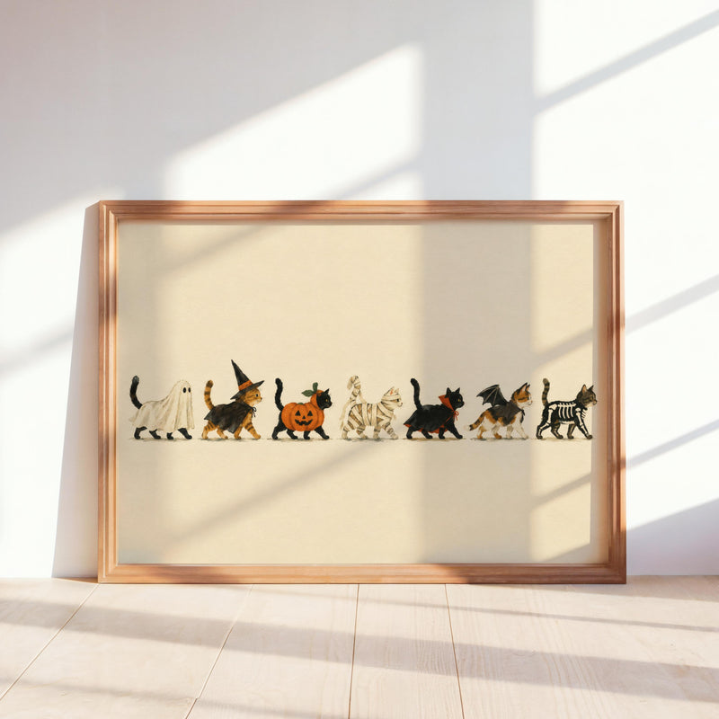 Framed horizontal Halloween cat wall art leaning on sunlit floor, cream background, playful parade.