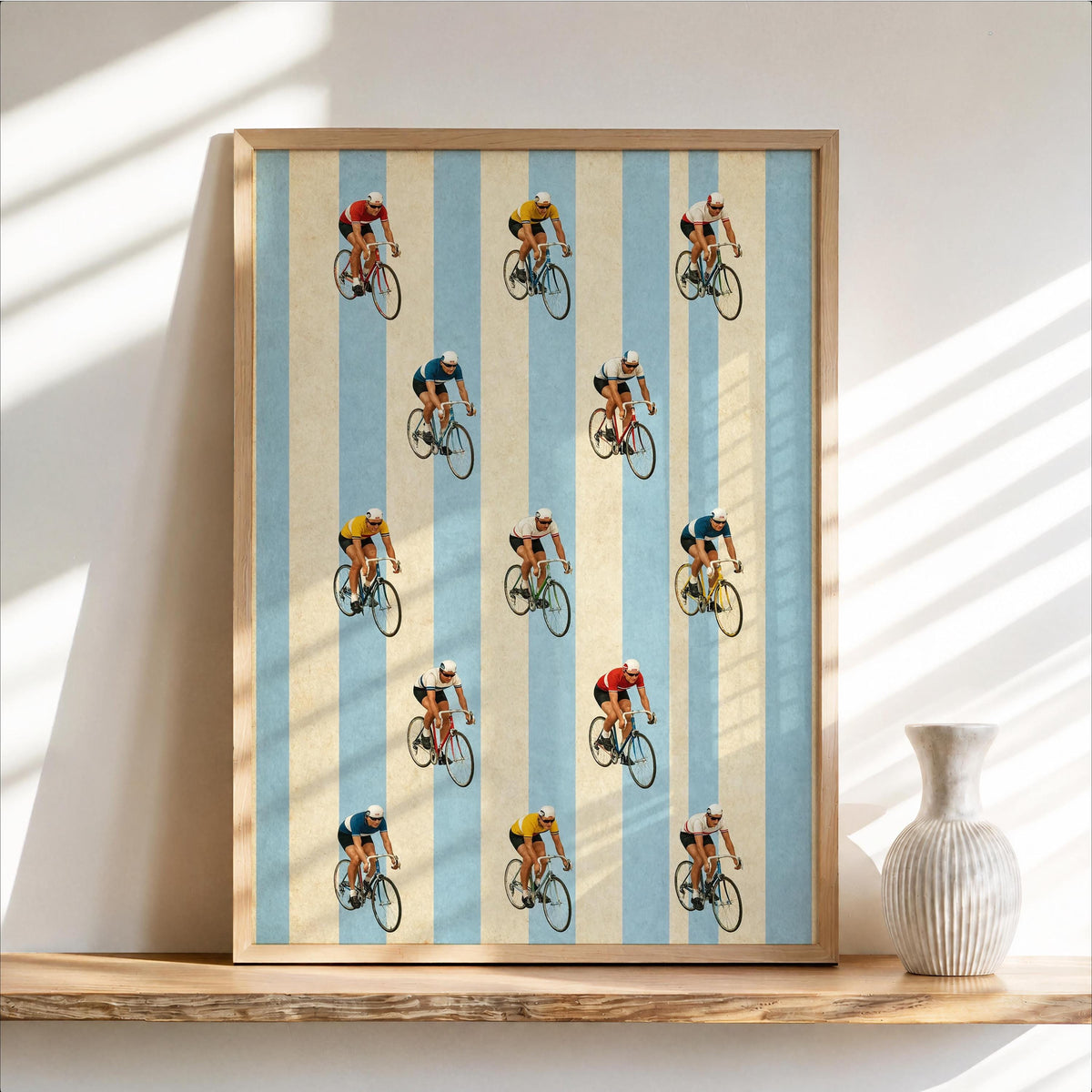 Framed retro cycling wall art leaning on a shelf, pale blue and cream stripes, playful cyclists.
