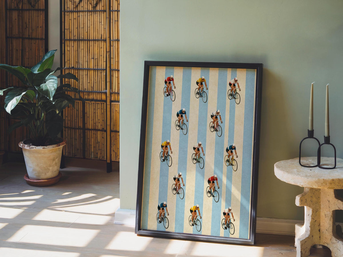 Tall retro cycling wall art near plant and rattan screen, mid-century vibe, colorful bicycle riders.
