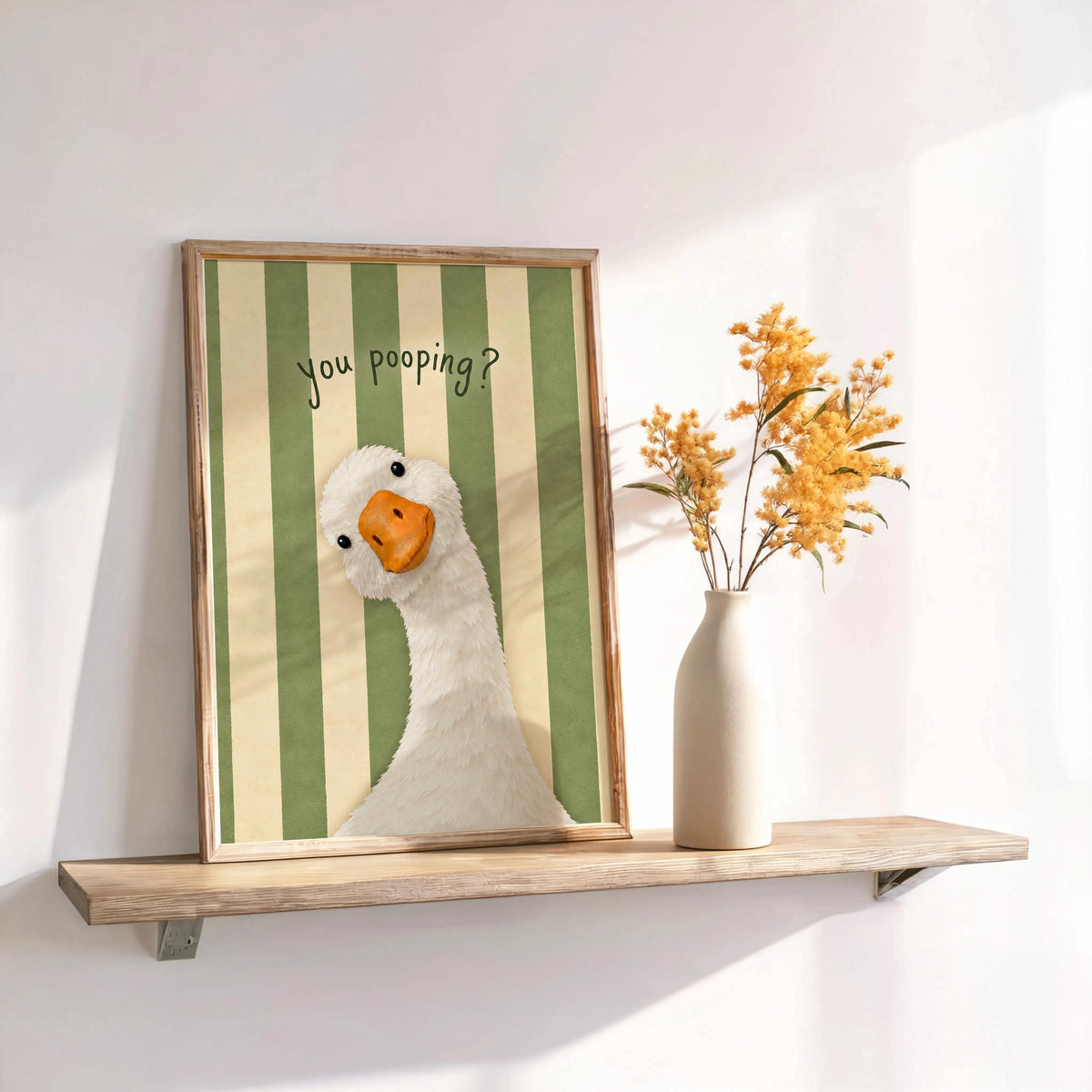 Framed green striped funny goose bathroom print on shelf, bright powder room wall decor with subtle shadows