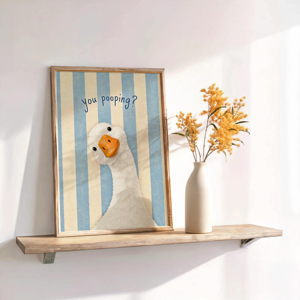 Blue striped framed funny goose bathroom print on shelf, styled as powder room wall decor with dried flowers
