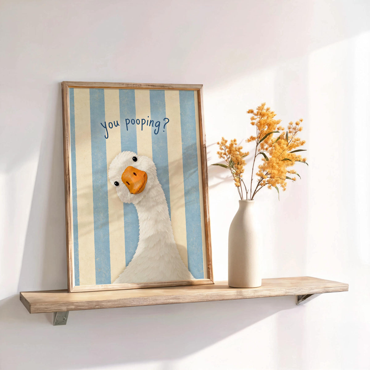 Blue striped framed funny goose bathroom print on shelf, styled as powder room wall decor with dried flowers