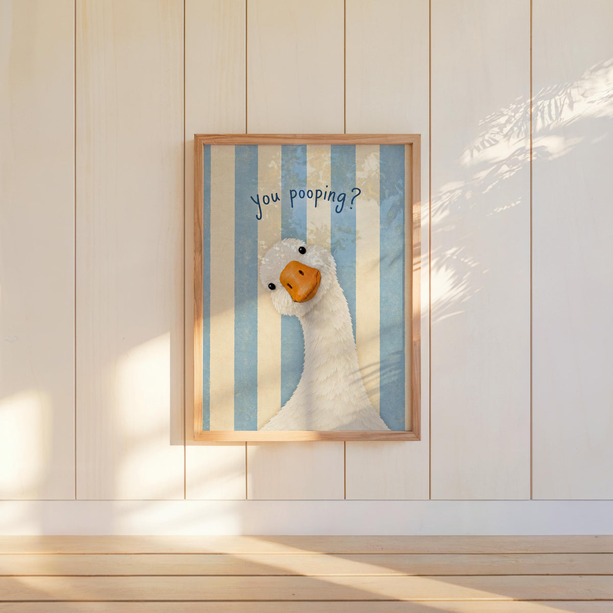 Framed blue striped funny goose bathroom print hanging on paneled wall, playful striped goose print for restroom