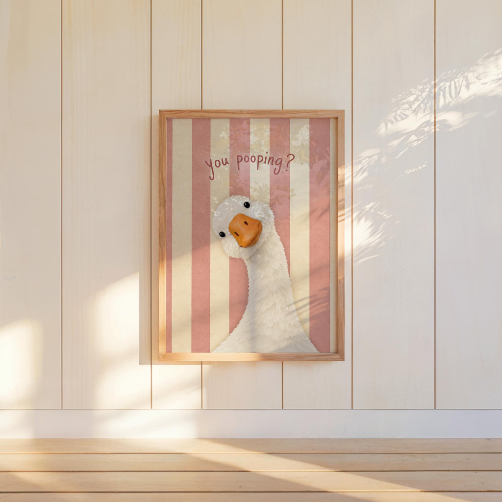Pink striped framed funny goose bathroom print hung on paneled wall, silly goose bathroom decor, playful tone